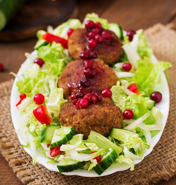 Sappige vleeskoteletten met Amerikaanse veenbessaus en salade op een houten lijst in een rustieke stijl.