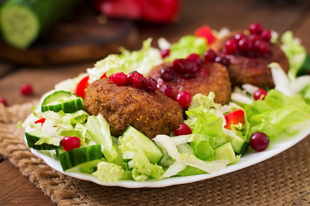 Sappige vleeskoteletten met Amerikaanse veenbessaus en salade op een houten lijst in een rustieke stijl.