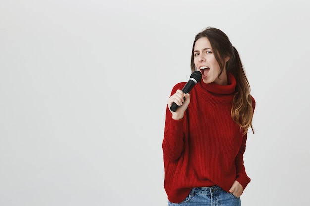Sassy aantrekkelijke vrouw die in microfoon zingt