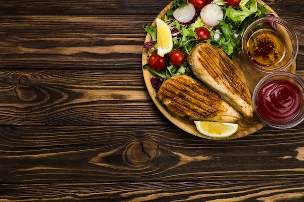 Saus en specerijen in de buurt van salade en kip