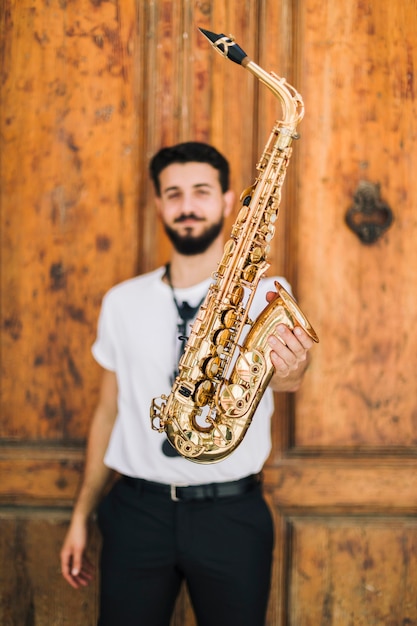 Gratis foto saxofoon die door defocused musicus wordt gehouden