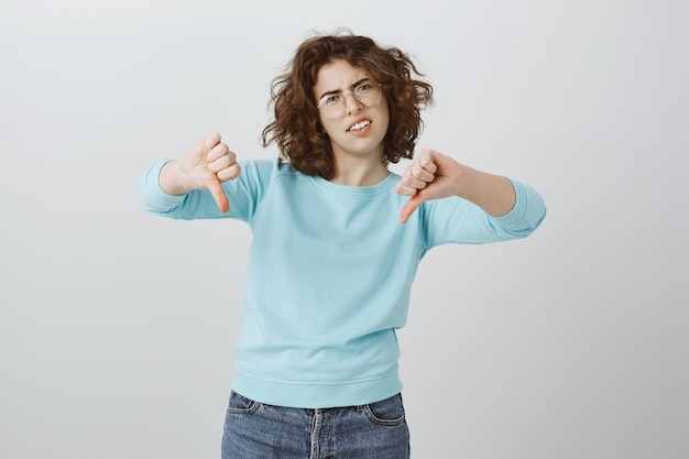 Sceptische en teleurgestelde vrouw die duimen toont, zeer slecht, vreselijk resultaat, afkeer