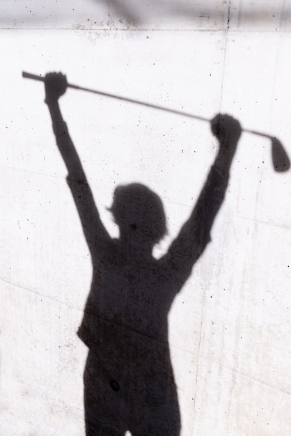 Gratis foto schaduw van een golfer op de muur onder de lichten