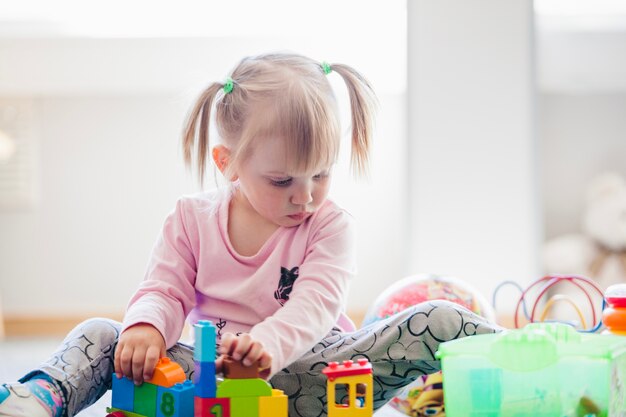 Schattig kind met speelgoed in speelkamer