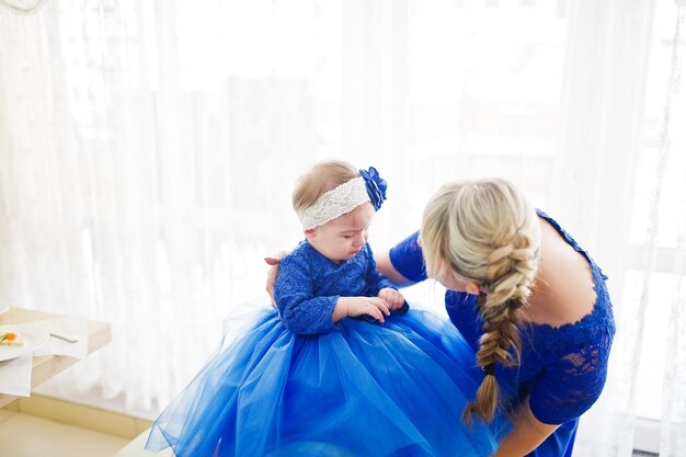 Schattig klein babymeisje bij blauwe jurk in handen van moeder