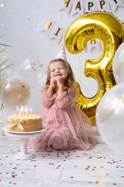 Schattig klein kindmeisje blaast kaarsen op verjaardagstaart en viert verjaardag Premium Foto