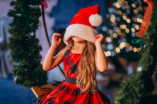 Schattig klein meisje in kerstmuts en rode jurk