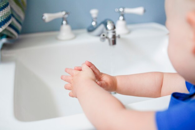Schattig klein meisje leert hoe ze haar handen moet wassen in het nieuwe normaal