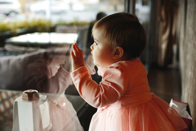 Gratis foto schattig klein meisje legt haar handen op het raam