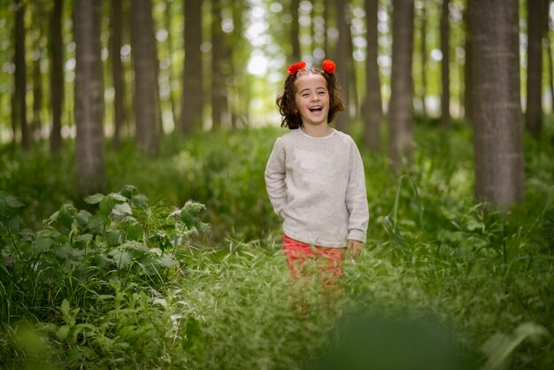 Schattig klein meisje met vier jaar oud met plezier in een bos van populieren