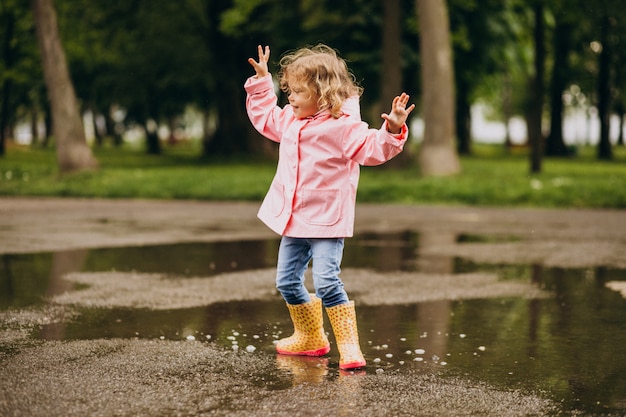 Schattig klein meisje springen in plas in een regenachtig weer