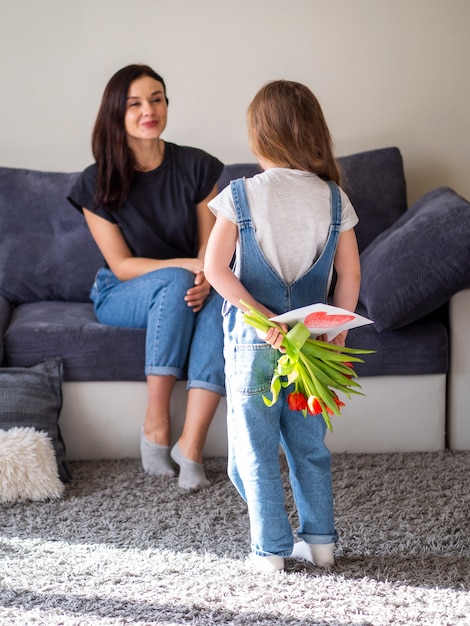 Gratis foto schattig klein meisje verrassende moeder met bloemen