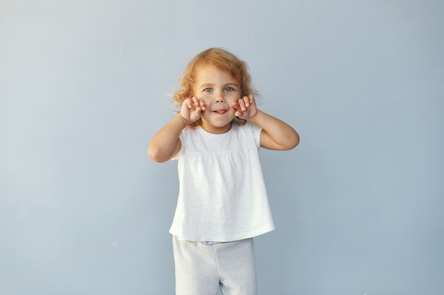 Schattig klein meisje, zittend in een studio op een blauwe achtergrond