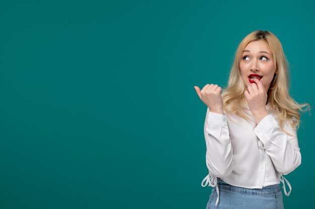 Schattig meisje blond jong mooi meisje in een wit overhemd een vinger bijten en dromen van iets