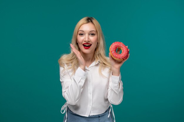 Schattig meisje blond mooi jong meisje in een wit netjes shirt erg blij voor een bessen donut