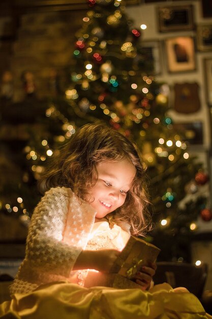 Schattig meisje lacht en kijkt naar haar kerstcadeau