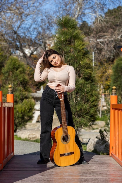 Schattig meisje met haar gitaar in het park Foto van hoge kwaliteit