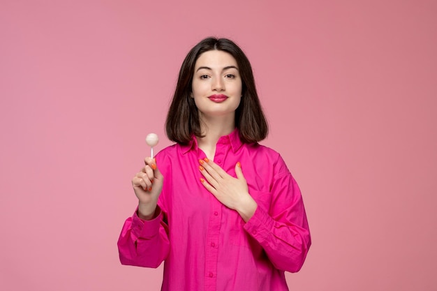 Schattig meisje, mooie jonge brunette meisje in roze shirt met borst met zoete lolly