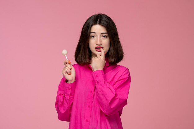 Schattig meisje mooie jonge brunette meisje in roze shirt met rode lippenstift bijtende vinger