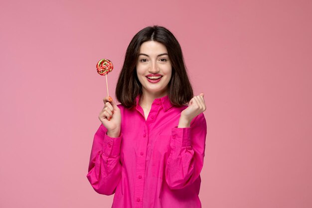 Schattig meisje mooie jonge mooie brunette meisje in roze shirt blij met een ronde lolly