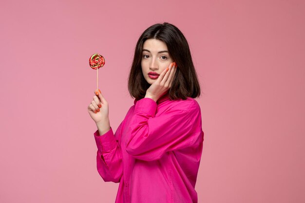 Schattig meisje mooie jonge mooie brunette meisje roze shirt met gezicht en ronde zoete lolly