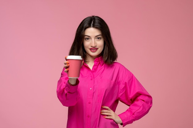 Schattig meisje, mooie schattige mooie dame met rode lippenstift in roze shirt die een roze papercup geeft