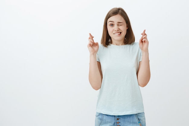 schattig opgewonden en hoopvolle vrouwelijke fan kijkt naar belangrijk spel gluren met één oog en kruist vingers voor geluk nerveus voelen observeren belangrijk spel van favoriete team