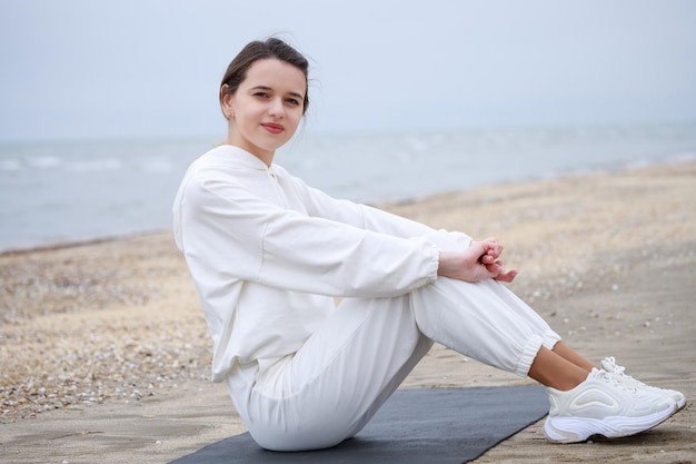 Schattige atleet op het strand zit op de yogamat Hoge kwaliteit foto