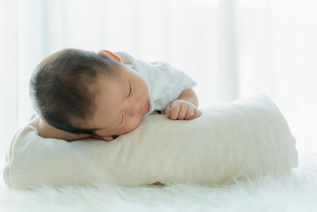 Schattige baby babyjongen slaap met zoete droom en vredig wit zacht bed