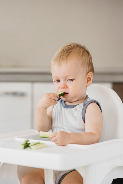 Schattige baby eet alleen in zijn kinderstoel