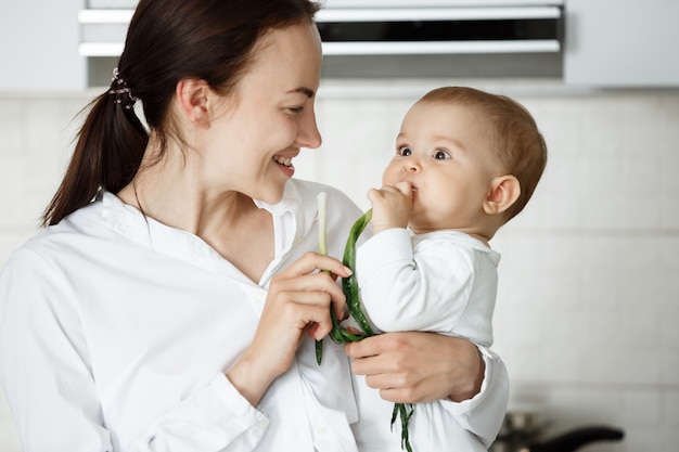 Schattige baby en haar moeder groene ui eten