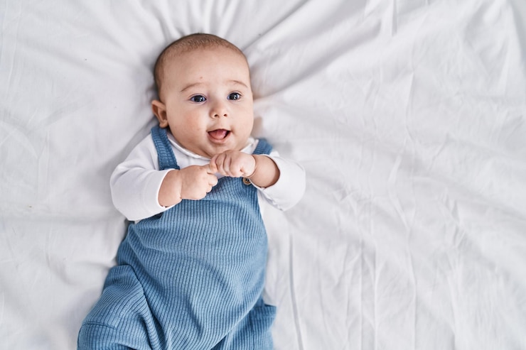 Gratis Foto schattige baby glimlachend zelfverzekerd liggend op bed in de slaapkamer