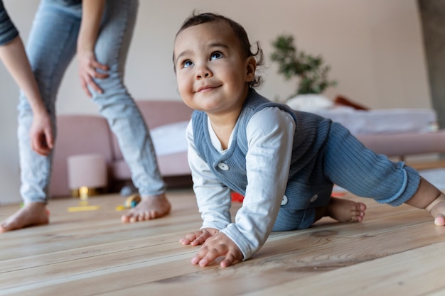 Schattige baby lacht en kruipt op de grond met zijn moeder naast hem