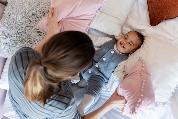 Schattige baby lacht en speelt met zijn moeder op bed