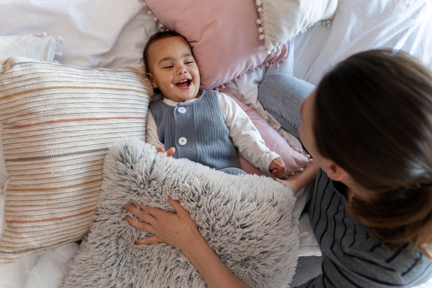 Schattige baby lacht en speelt met zijn moeder op bed