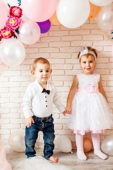 Schattige baby's - jongen en meisje houden handen rond de ballonnen. het jongetje kijkt enthousiast naar zijn vriendin