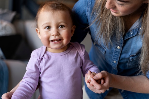 Schattige baby wordt vastgehouden door zijn moeder en zit op de grond