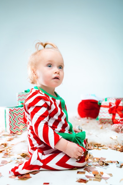 Schattige babymeisje 1 jaar oud in de buurt van kerstmuts poseren met Kerstmis