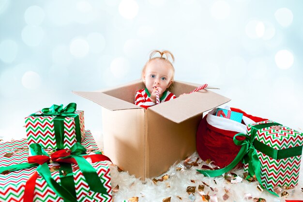 Schattige babymeisje, zittend in doos op Kerst achtergrond. Vakantie, feest, kind concept