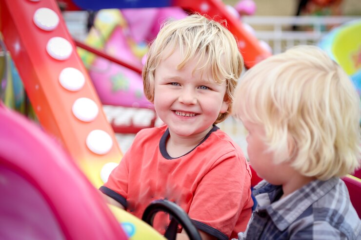 Schattige blonde Australische kinderen zitten op kinderattractie