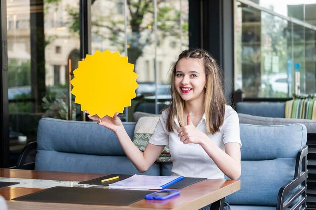 Schattige blonde bedrijf idee board en gebaar duim omhoog in het restaurant