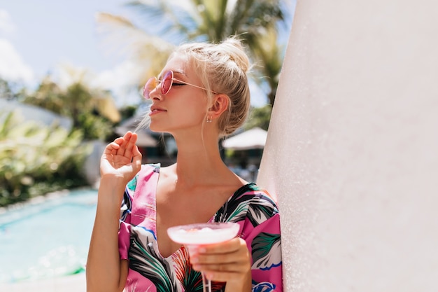 Schattige blonde vrouw genieten van zonneschijn in het resort.