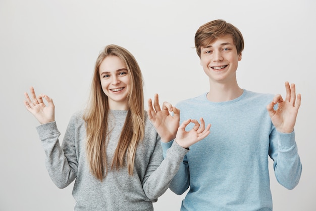 Gratis foto schattige broers en zussen met beugels, gelukkig lachend en toon goed gebaar