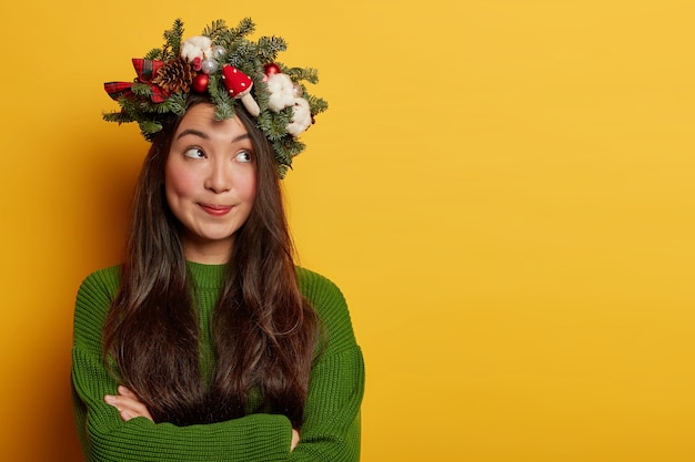 Schattige jonge dame glimlacht aangenaam met feestelijke krans op het hoofd