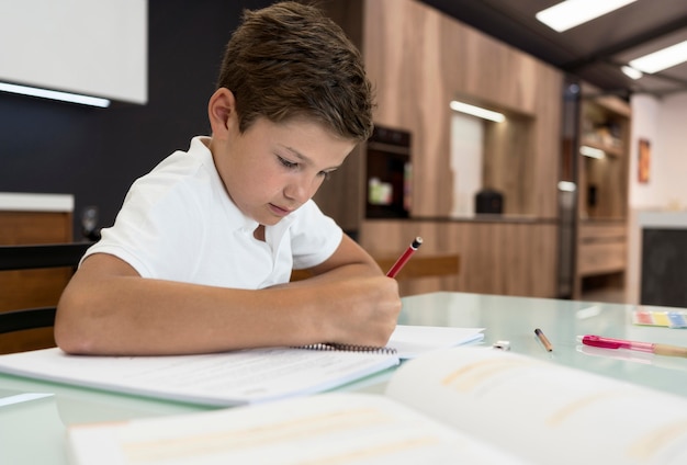 Gratis foto schattige jonge jongen die zijn huiswerk doet