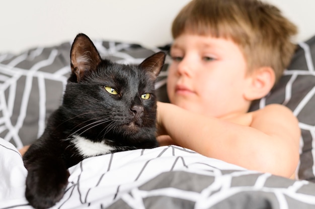 Gratis foto schattige jonge jongen die zijn kat aait