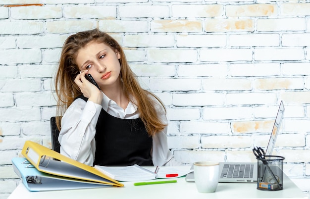 Schattige jonge student zittend op een witte achtergrond en praten aan de telefoon Hoge kwaliteit foto