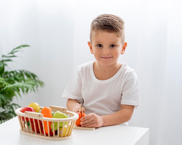 Gratis foto schattige jongen groenten snijden