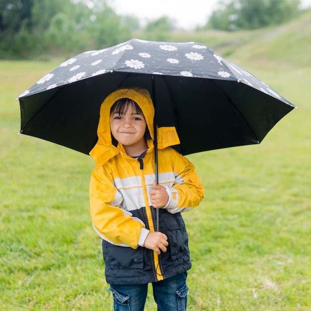 Gratis foto schattige jongen in regenjas en paraplu