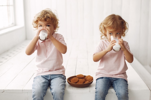 Schattige kinderen eten koekjes en consumptiemelk